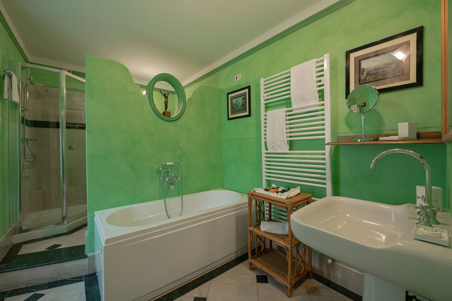 Modern bathroom featuring a green color scheme, a bathtub, a shower area, a sink with a stylish faucet, and decorative elements like framed pictures and a wooden storage rack. | Only on SopranoVillas