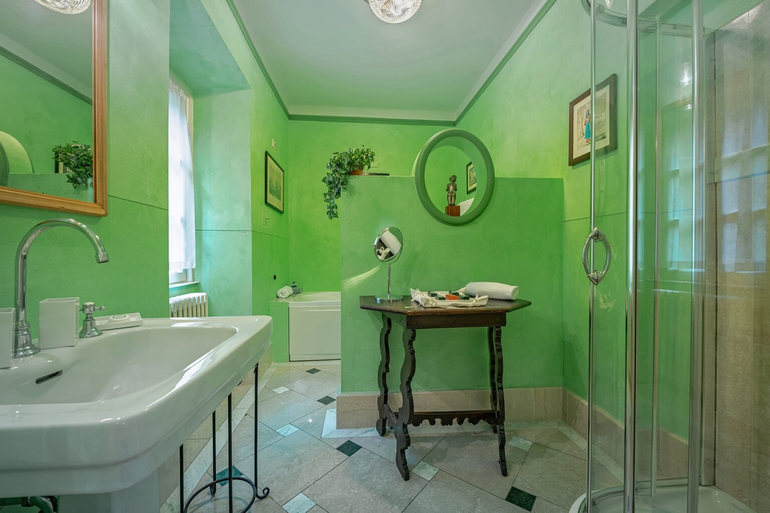 Bright green bathroom featuring a modern shower, decorative plants, and elegant furnishings. The space includes a vintage-style table and stylish mirror, creating a refreshing and inviting atmosphere. | Only on SopranoVillas