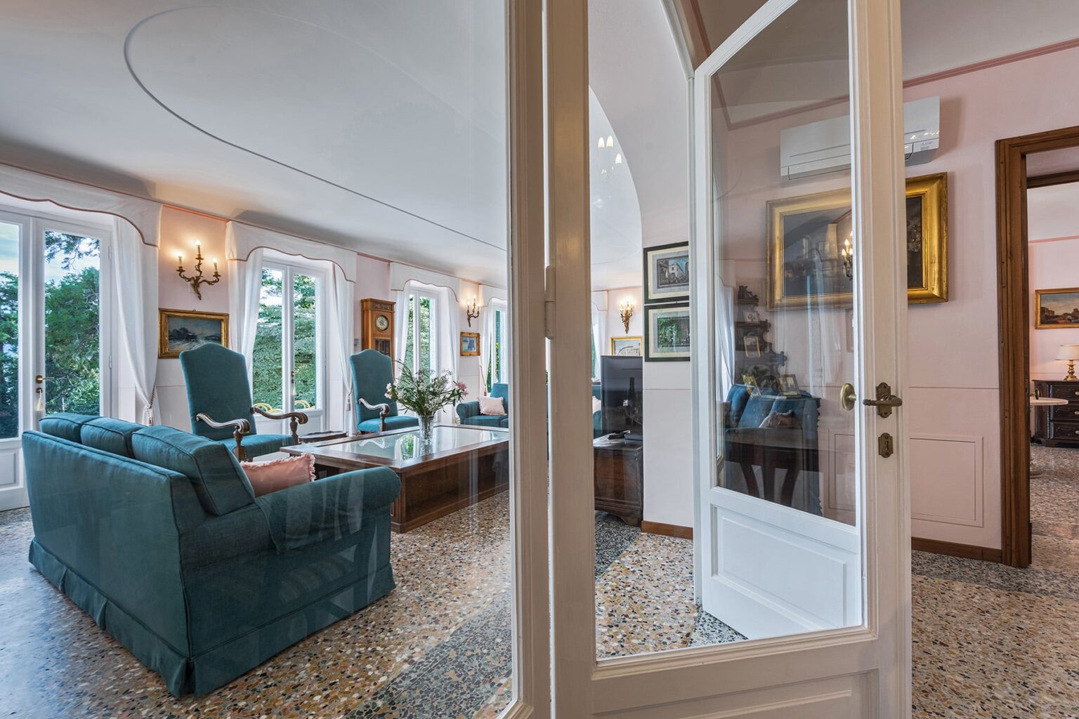 Spacious living room with elegant furniture, large windows providing natural light, and decorative artwork, showcasing a welcoming and comfortable ambiance. | Only on SopranoVillas