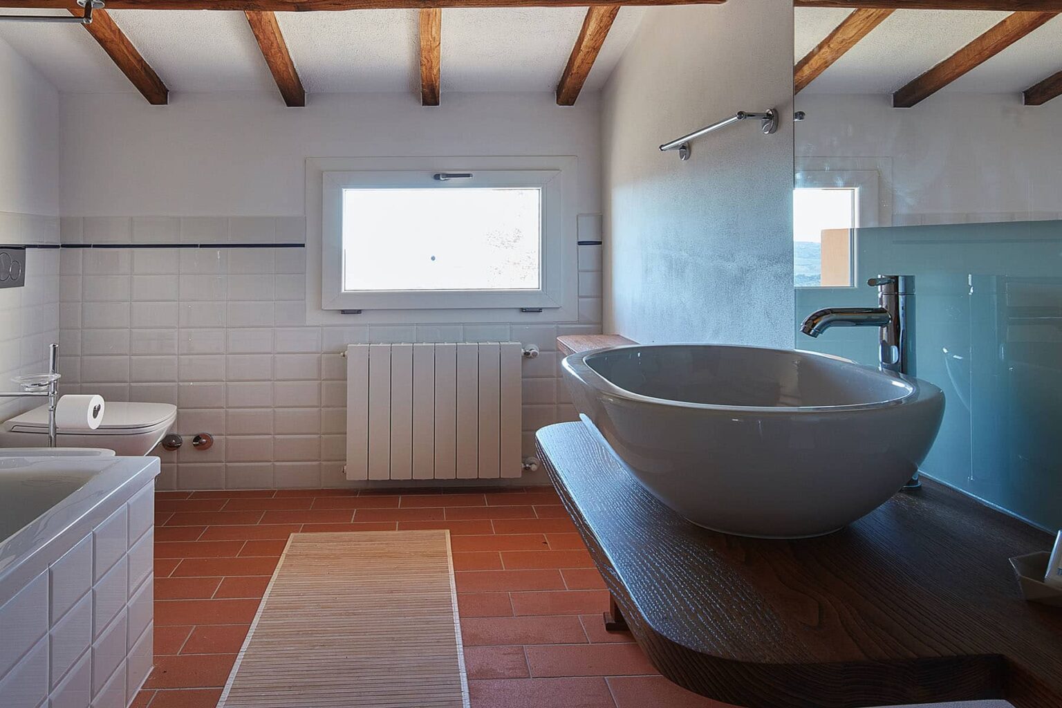 Modern bathroom interior featuring a freestanding sink, wooden countertop, large window for natural light, and minimalist decor with beige tiles and wooden beams. | Only on SopranoVillas