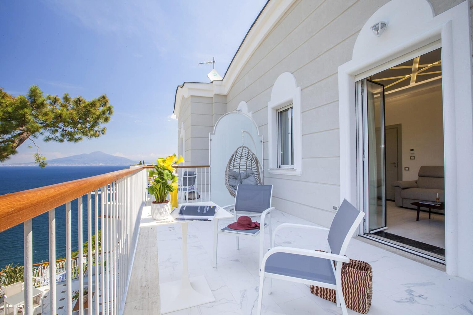 Bright coastal balcony with modern furniture, featuring a stunning sea view and lush greenery, perfect for relaxation. | Only on SopranoVillas