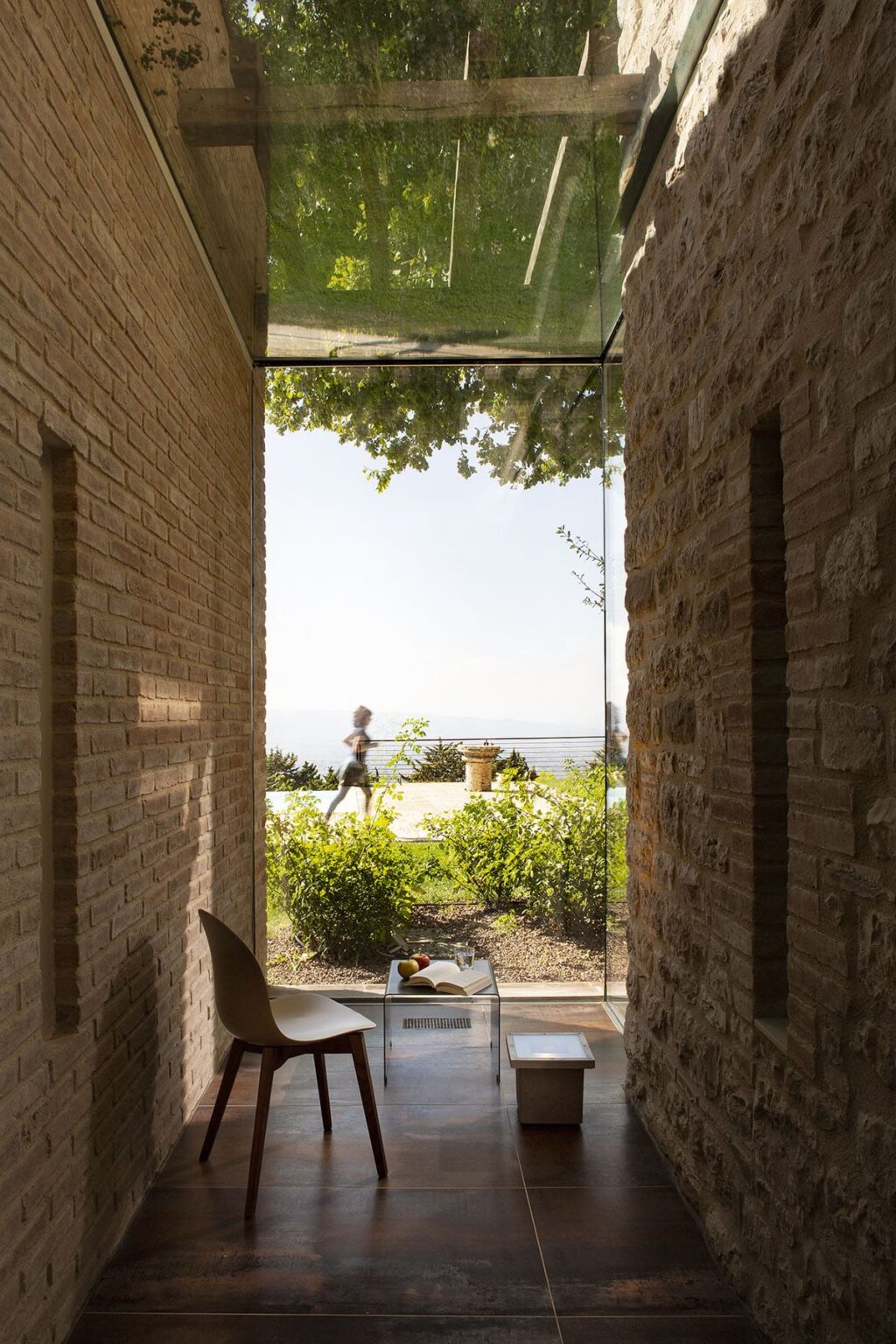 A person jogging through a stone archway with a view of lush greenery and a distant landscape under a clear sky, showcasing an outdoor lifestyle and architectural design. | Only on SopranoVillas