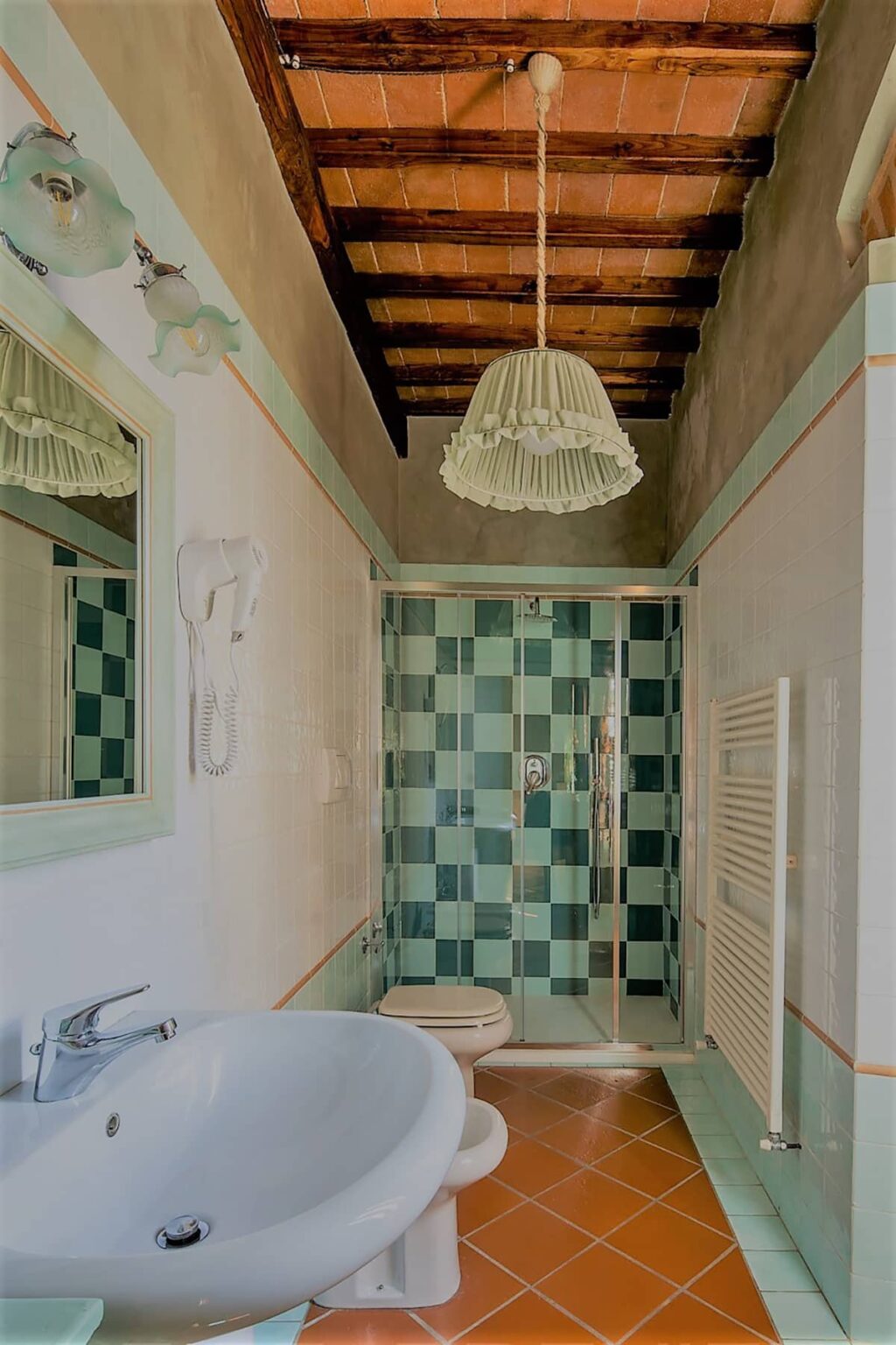 Stylish bathroom featuring a glass shower with green and white checkered tiles, a decorative ceiling light, and a mirror reflecting the modern design elements. | Only on SopranoVillas