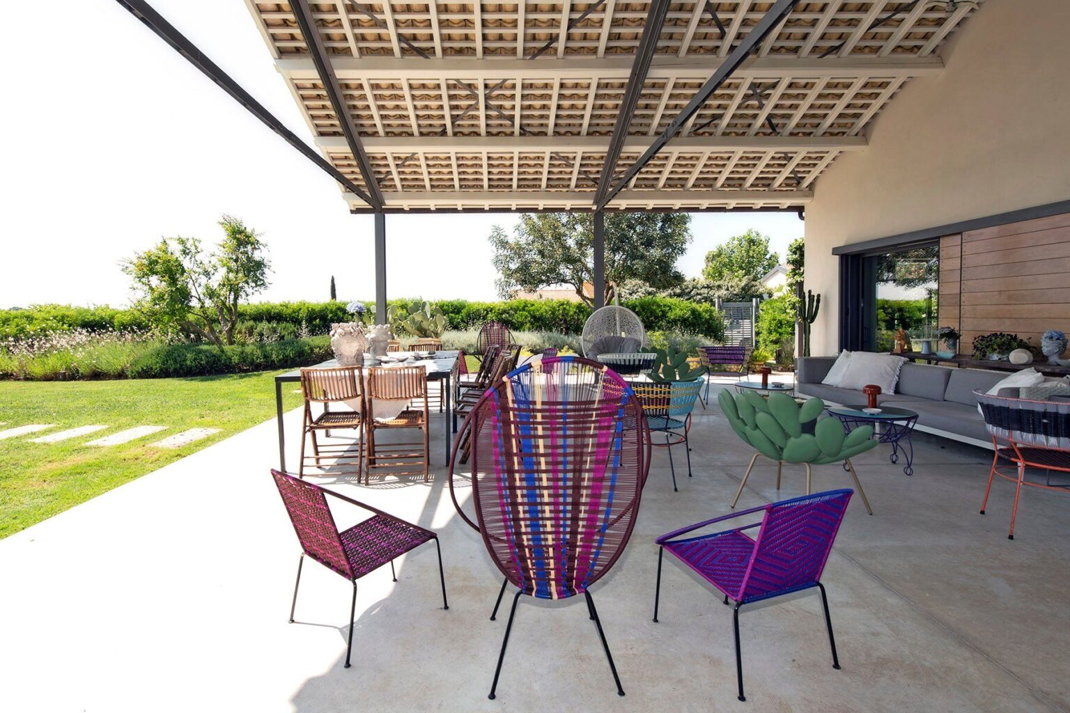 Colorful outdoor seating area featuring modern chairs under a spacious patio, surrounded by greenery and a stylish table set for dining. Ideal for entertaining and enjoying nature. | Only on SopranoVillas