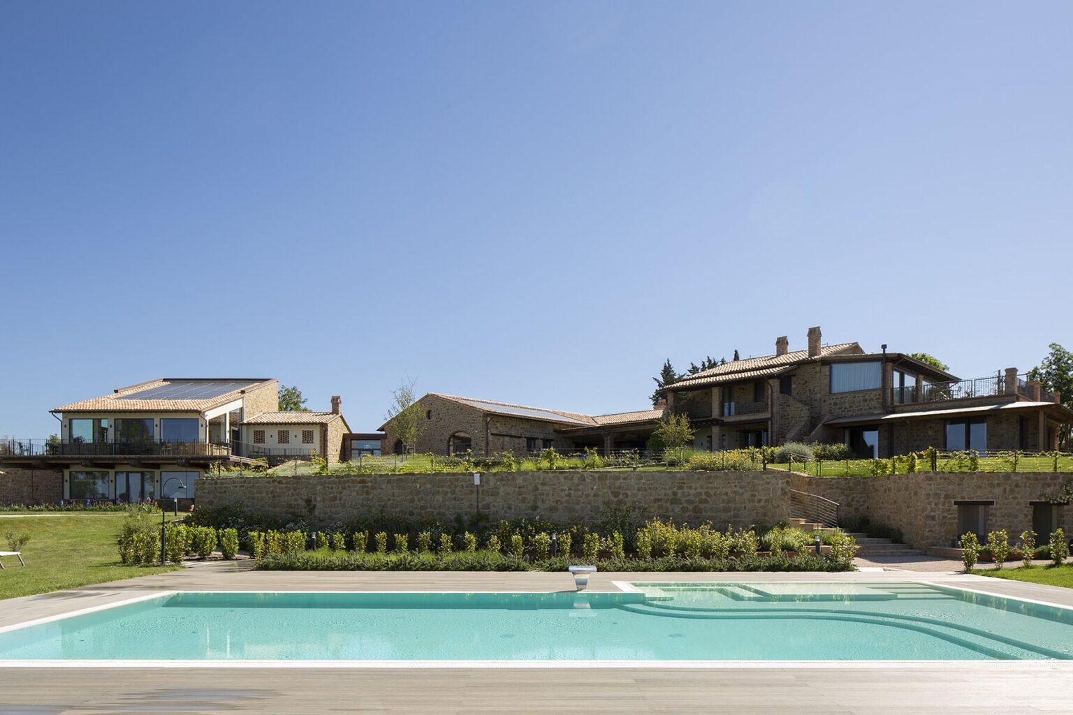 Modern luxury villas with a swimming pool and landscaped gardens under a clear blue sky. | Only on SopranoVillas