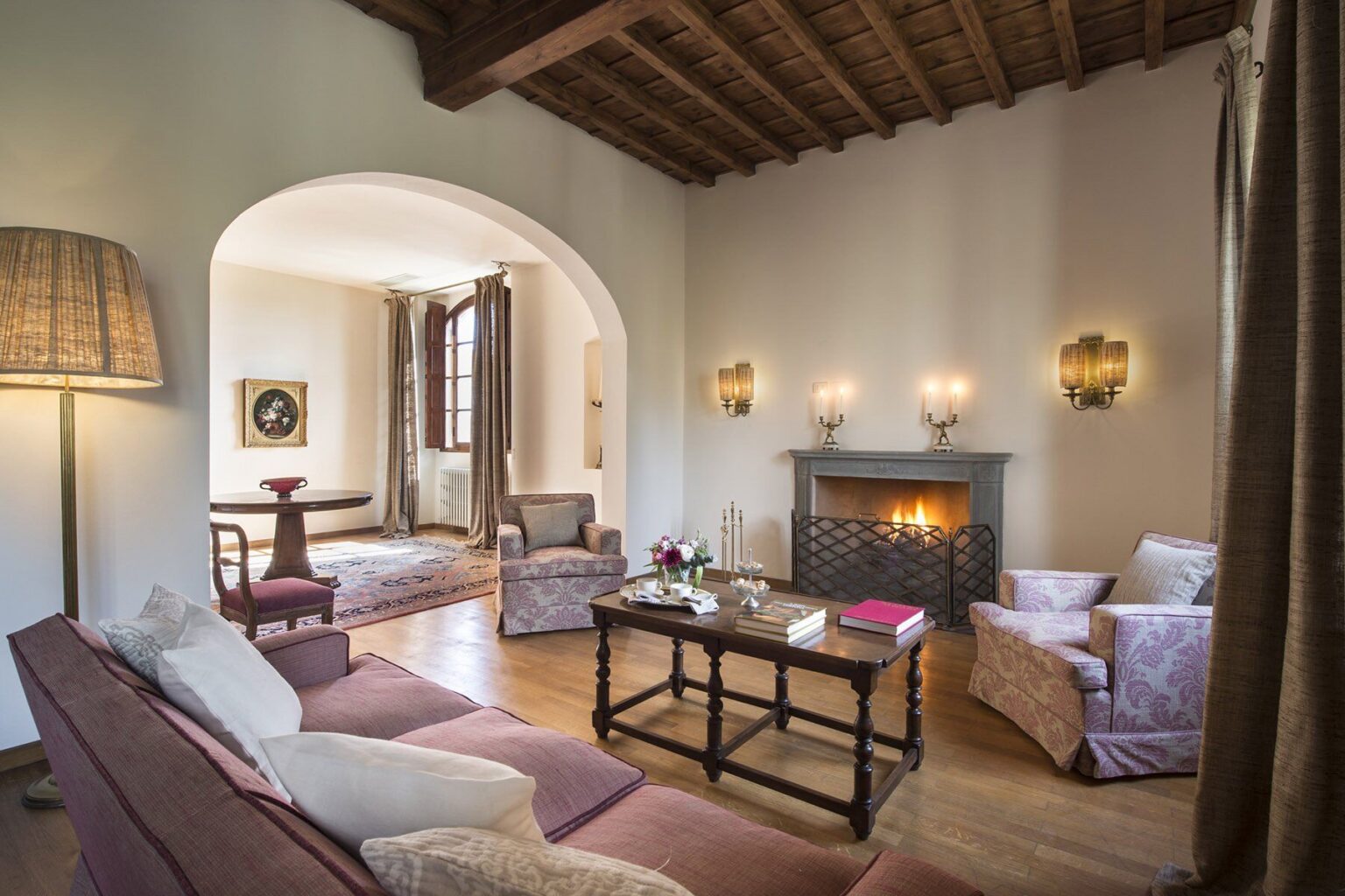 Cozy living room featuring a fireplace, elegant furniture, and warm lighting, with wooden beams on the ceiling and soft decor elements, ideal for relaxation and gatherings. | Only on SopranoVillas