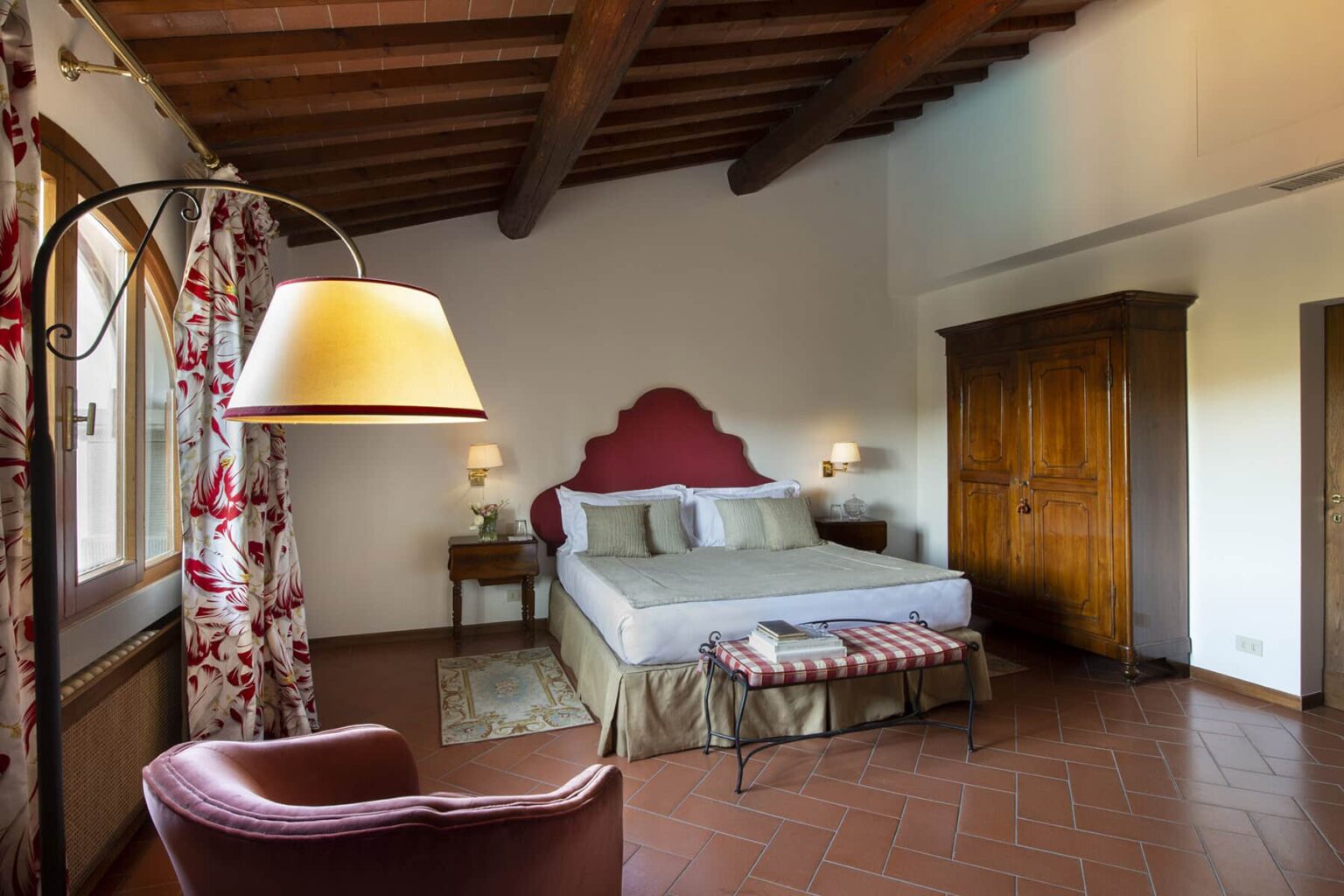 Cozy bedroom featuring a king-size bed with decorative headboard, elegant curtains, wooden wardrobe, and stylish floor lamp, all under a rustic ceiling with exposed beams. Ideal for a relaxing getaway. | Only on SopranoVillas