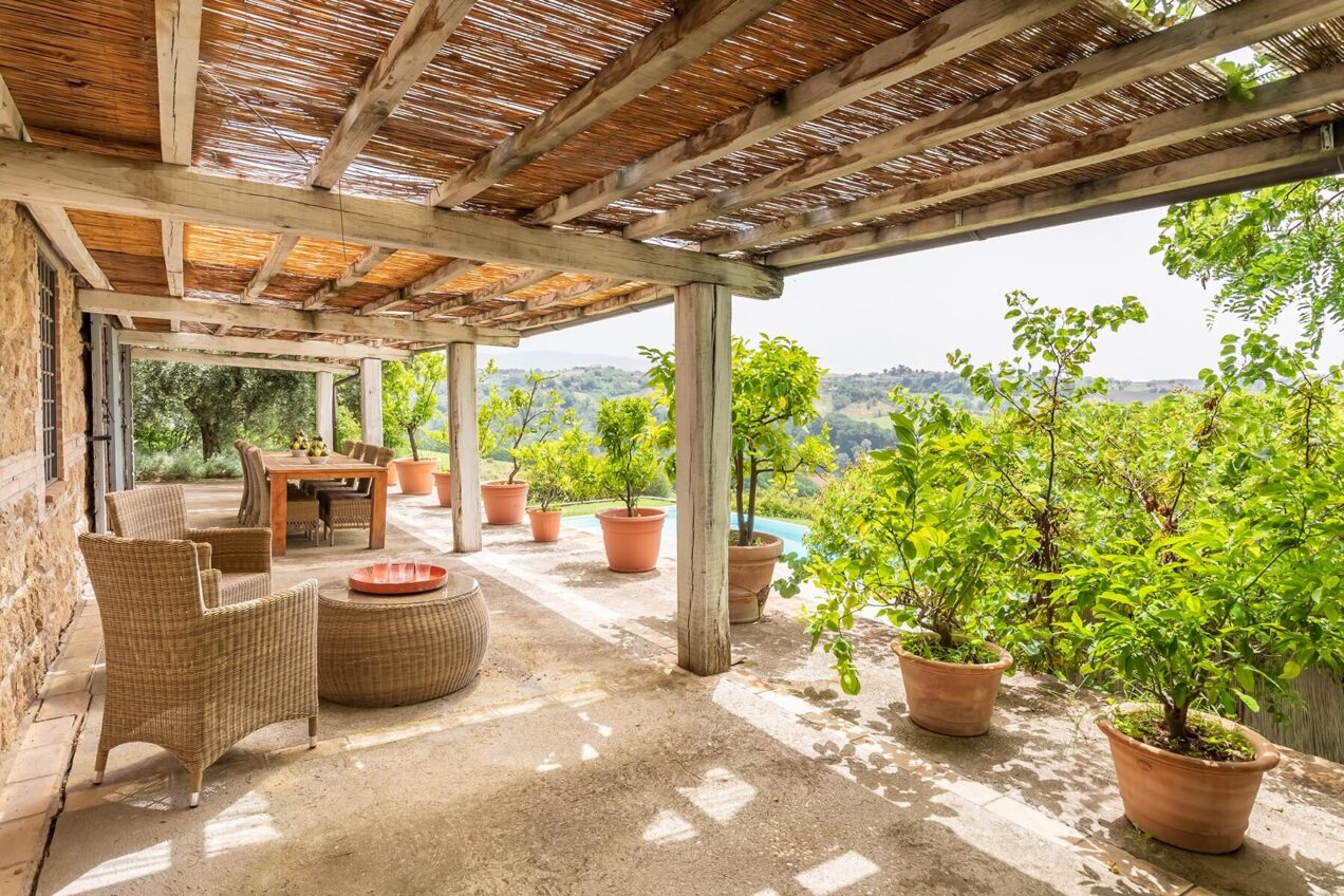 Charming outdoor patio with wicker furniture, potted plants, and a serene view, perfect for relaxation in a natural setting. | Only on SopranoVillas