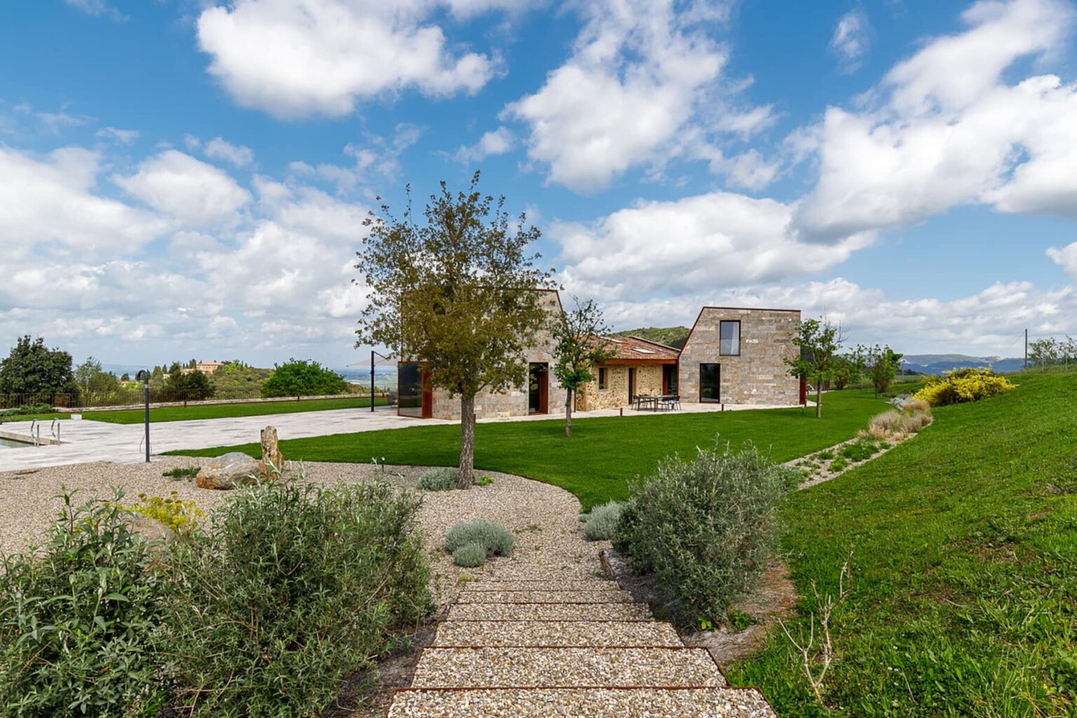 Beautiful countryside home surrounded by lush greenery and a well-maintained garden, featuring a stone exterior and a clear blue sky. Pathway leading to the entrance enhances the inviting atmosphere. Ideal for nature lovers and those seeking a serene retreat. | Only on SopranoVillas