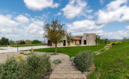 Beautiful countryside home surrounded by lush greenery and a well-maintained garden, featuring a stone exterior and a clear blue sky. Pathway leading to the entrance enhances the inviting atmosphere. Ideal for nature lovers and those seeking a serene retreat.