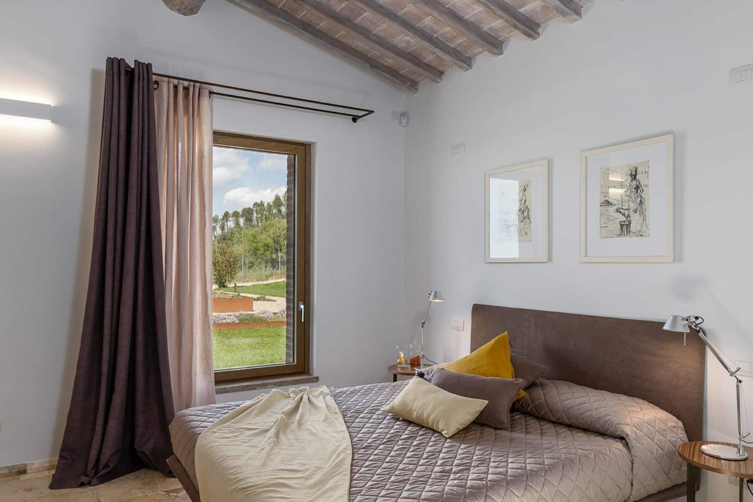 Cozy bedroom featuring a comfortable bed with decorative pillows, large window with scenic views, and elegant curtains. The room is adorned with framed artwork and has a modern aesthetic with wooden beams on the ceiling. Ideal for relaxation and comfort. | Only on SopranoVillas