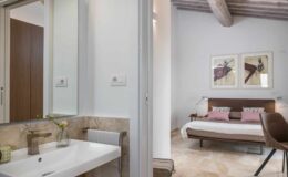 Modern bathroom and bedroom interior featuring a stylish sink, neutral color palette, and contemporary decor with artwork on the walls.