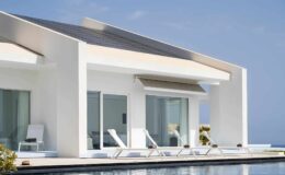 Modern white villa with large windows, sun loungers by the pool, and a clear blue sky in the background. Ideal for luxury vacation rentals or contemporary architecture inspiration.