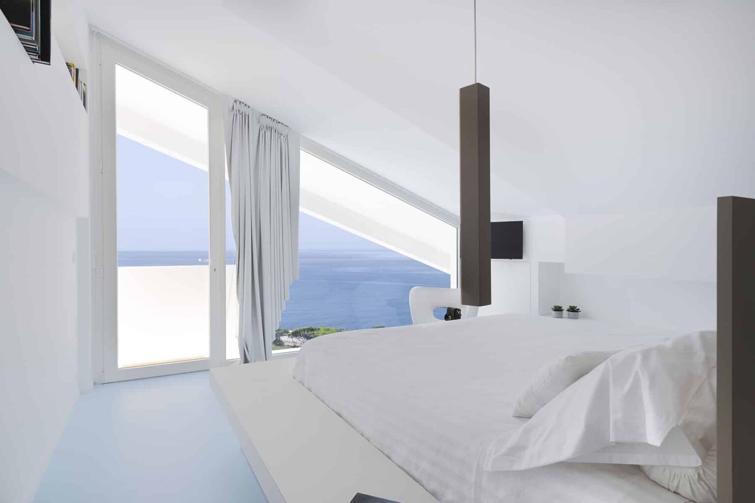 Modern bedroom with panoramic ocean view, featuring minimalist design, large windows, and soft white bedding. | Only on SopranoVillas