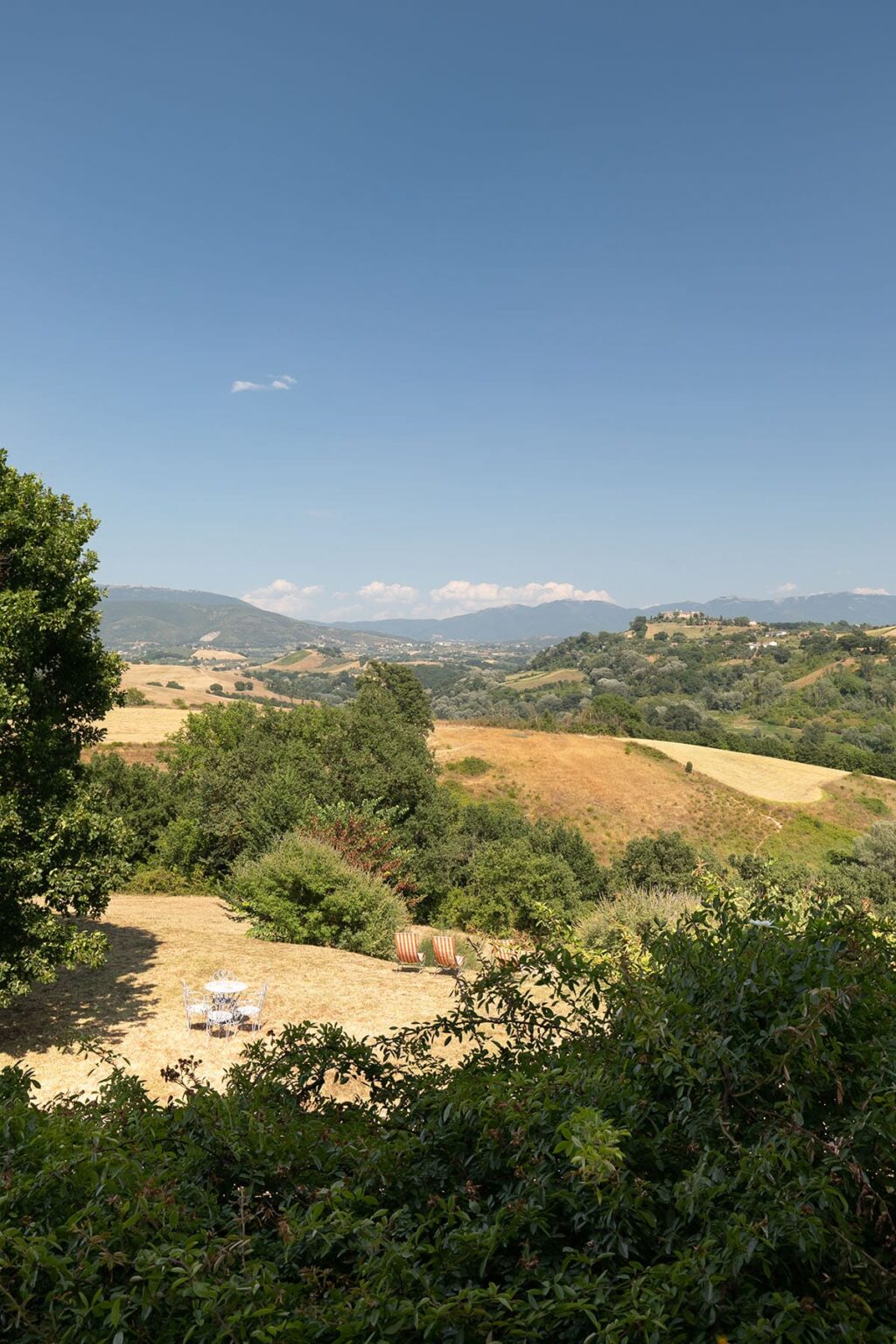 Scenic landscape featuring rolling hills and lush greenery under a clear blue sky, with distant mountains and fields in the background. Ideal for nature lovers and travel enthusiasts. | Only on SopranoVillas