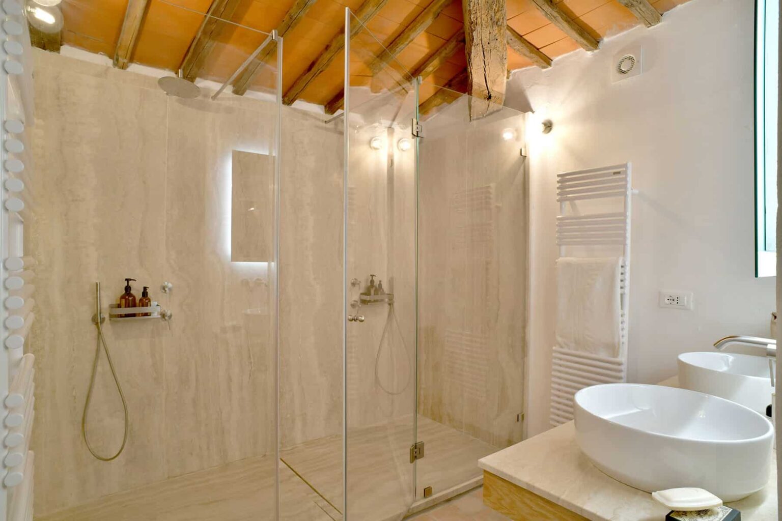 Modern bathroom featuring a spacious walk-in shower with glass enclosure, stylish double sinks, and wooden ceiling beams, creating a bright and airy atmosphere. | Only on SopranoVillas