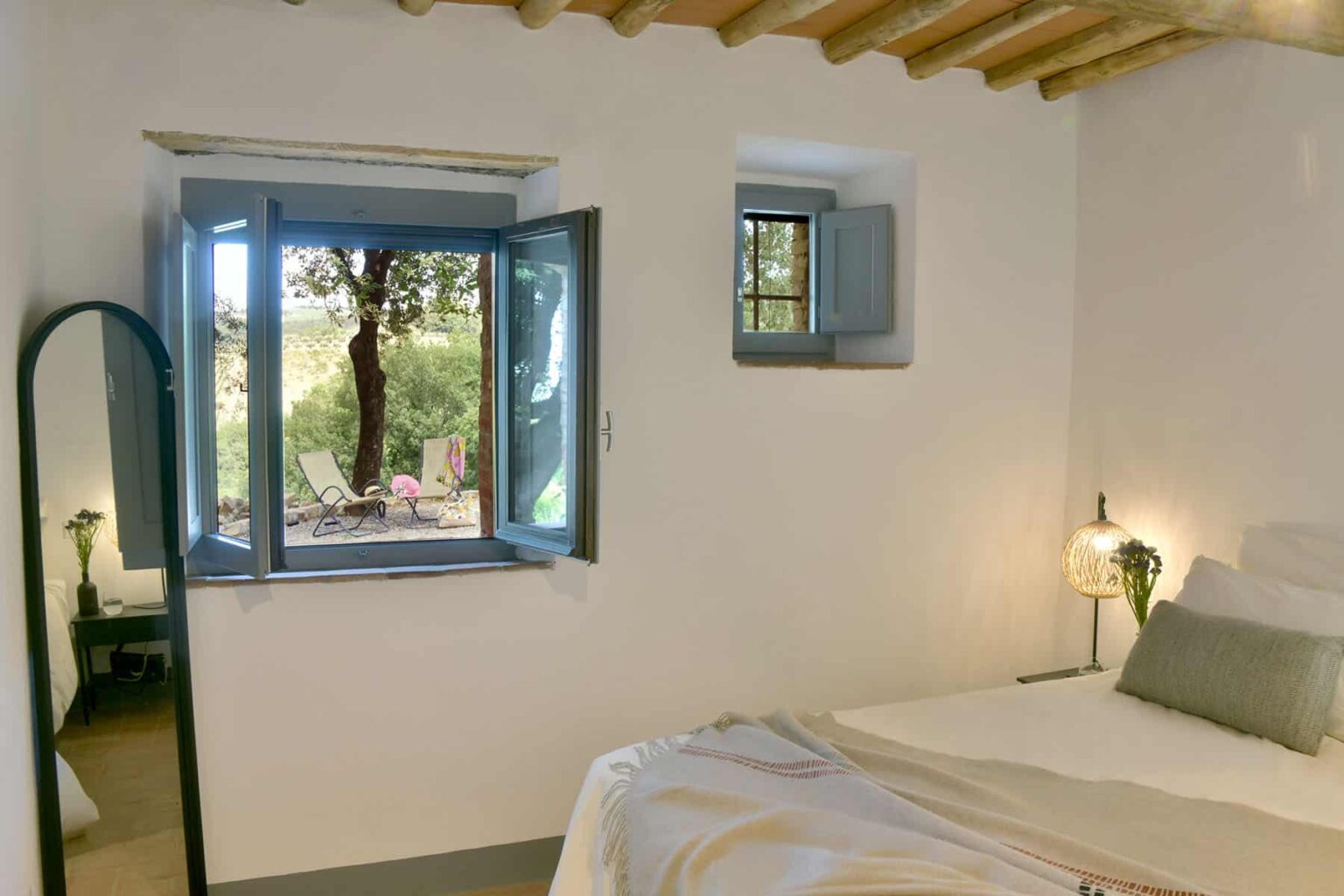 Cozy bedroom with a large window open to a scenic view, featuring a comfortable bed, minimalist decor, and natural light enhancing the space. | Only on SopranoVillas
