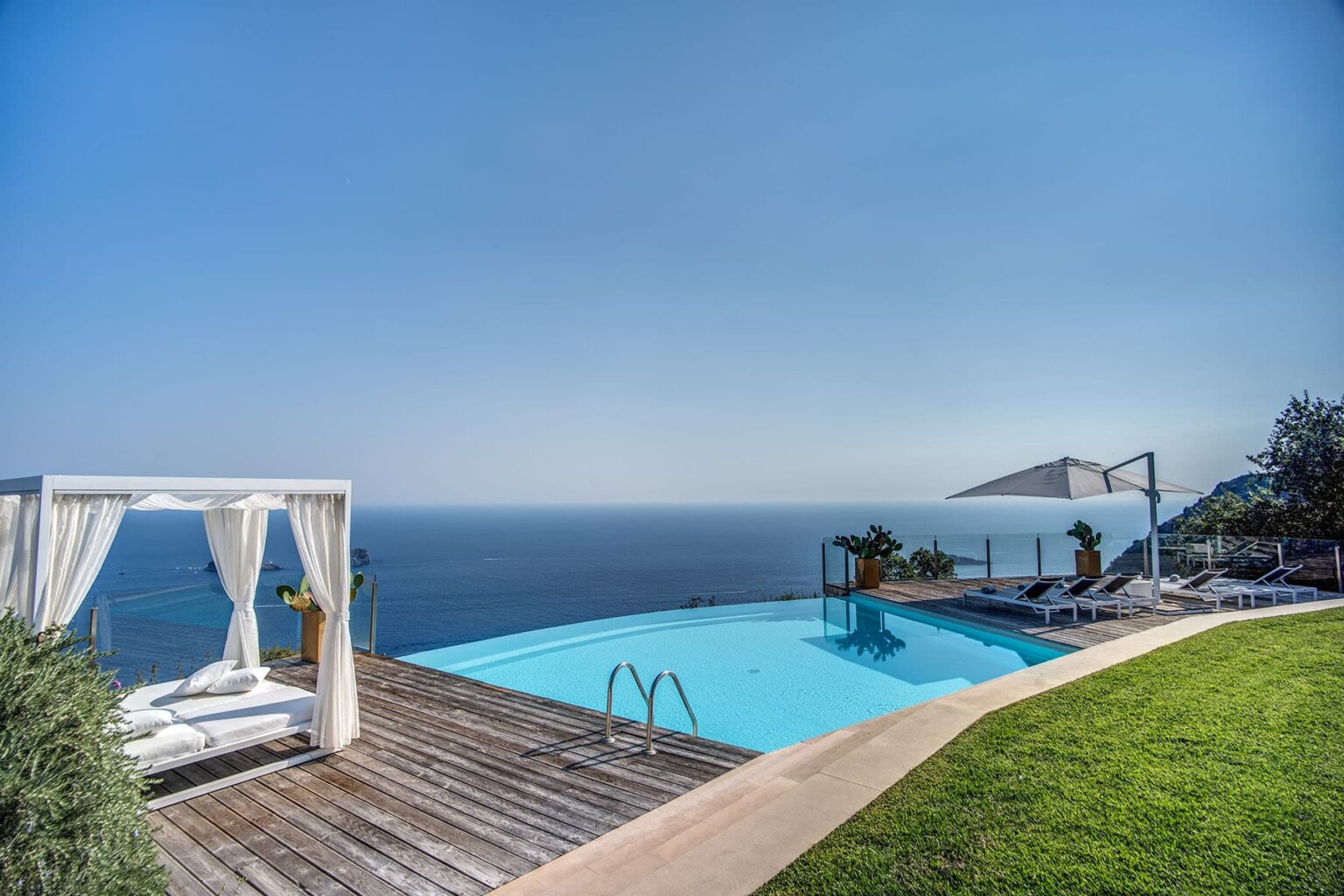 Luxury villa with an infinity pool overlooking the ocean, featuring a stylish outdoor seating area and lush green landscaping. Ideal for relaxation and enjoying scenic views. | Only on SopranoVillas