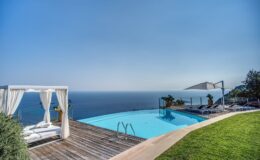 Luxury villa with an infinity pool overlooking the ocean, featuring a stylish outdoor seating area and lush green landscaping. Ideal for relaxation and enjoying scenic views.