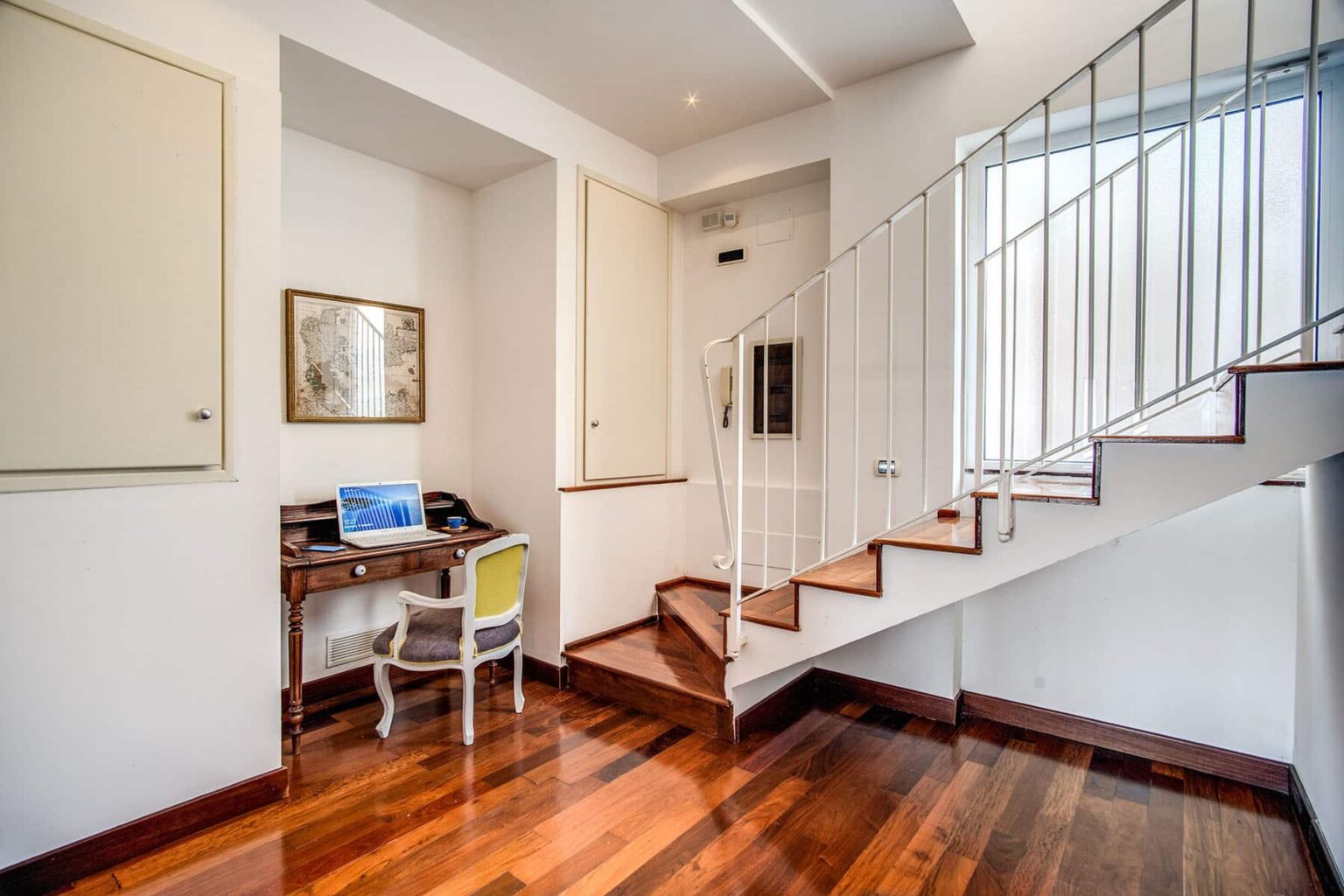 Modern home interior featuring a staircase, a small workspace with a desk and chair, and wooden flooring, creating a bright and inviting atmosphere. | Only on SopranoVillas