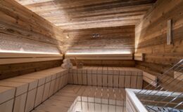Interior view of a modern wooden sauna featuring natural wood paneling, minimalist design, and ambient lighting for a relaxing atmosphere.