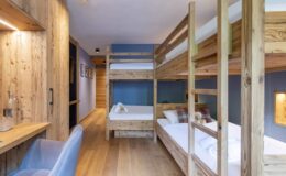 Cozy interior of a modern bunk bed room featuring wooden furniture, a spacious layout, and natural light, ideal for family or group stays.