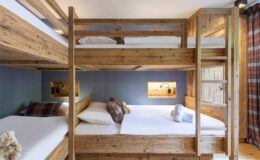 Cozy multi-level bunk bed room featuring rustic wooden furniture, comfortable bedding, and decorative pillows, ideal for group accommodations or family stays.