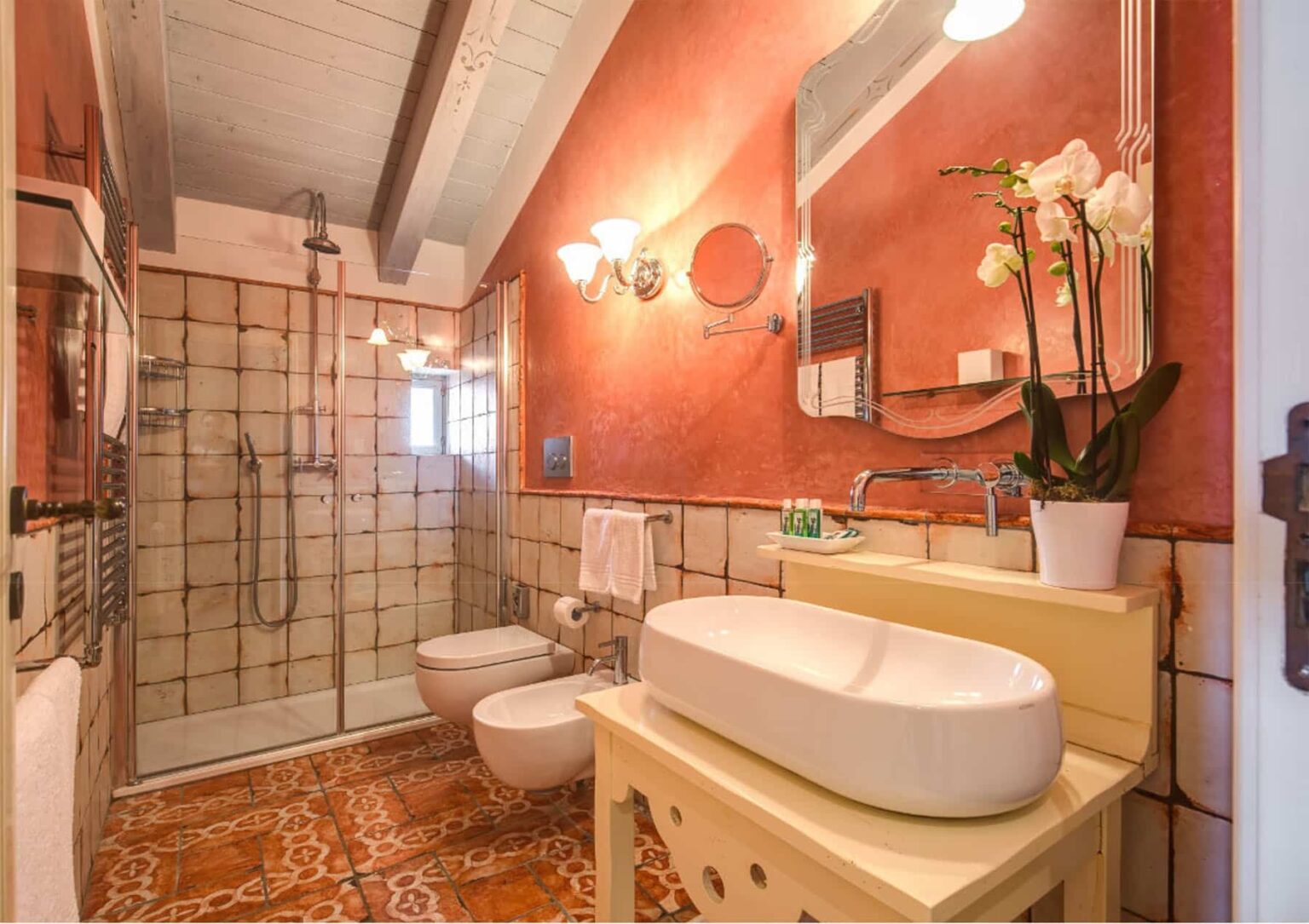 Modern bathroom interior featuring a spacious shower, stylish sink, and elegant decor with warm orange walls and decorative plants. Ideal for showcasing contemporary design and functionality. | Only on SopranoVillas