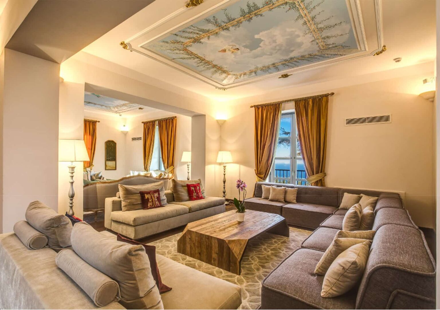 Spacious living room featuring elegant furniture, a decorative ceiling, warm lighting, and rich curtains, creating a cozy and inviting atmosphere. | Only on SopranoVillas