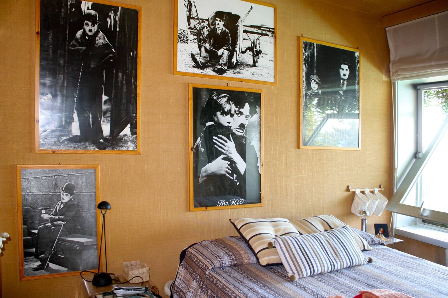 Cozy bedroom featuring a bed with striped bedding, adorned with various black and white photographs of classic cinema on the walls, creating a nostalgic atmosphere. | Only on SopranoVillas
