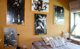 Cozy bedroom featuring a bed with striped bedding, adorned with various black and white photographs of classic cinema on the walls, creating a nostalgic atmosphere.