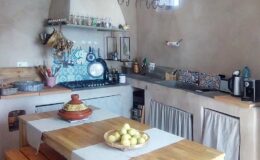 Bright and inviting kitchen with a wooden island, colorful tile backsplash, and modern appliances, featuring a bowl of fresh lemons on the countertop and natural light streaming through a window.
