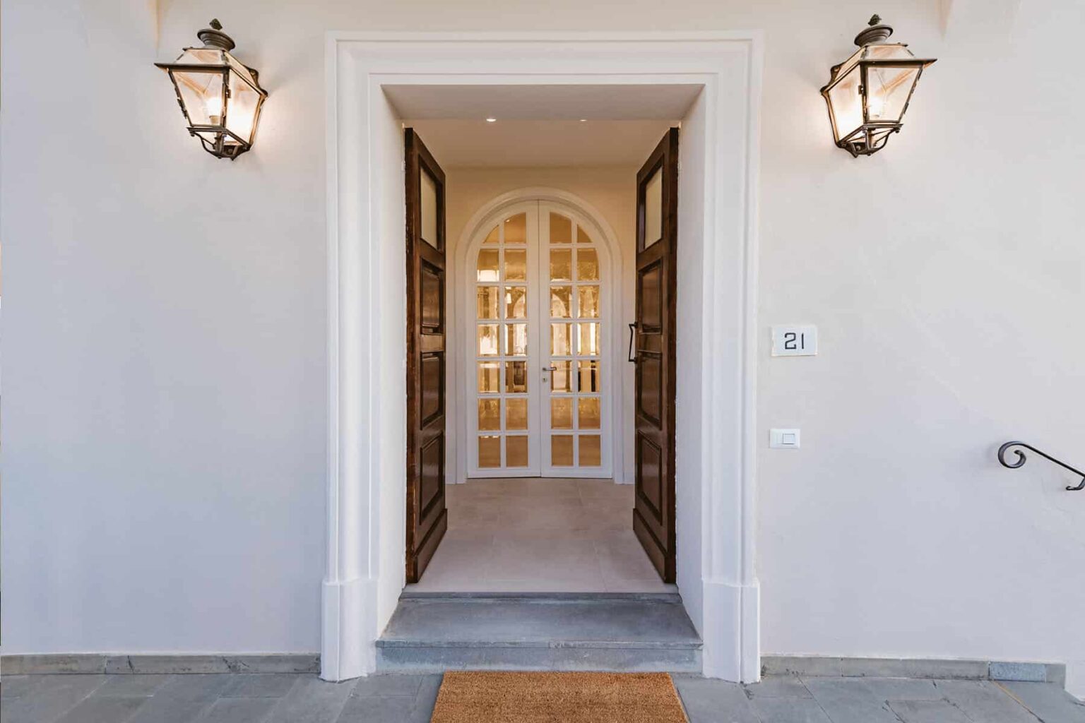 Elegant home entrance featuring double wooden doors, decorative lanterns, and a welcoming foyer with arched windows. | Only on SopranoVillas