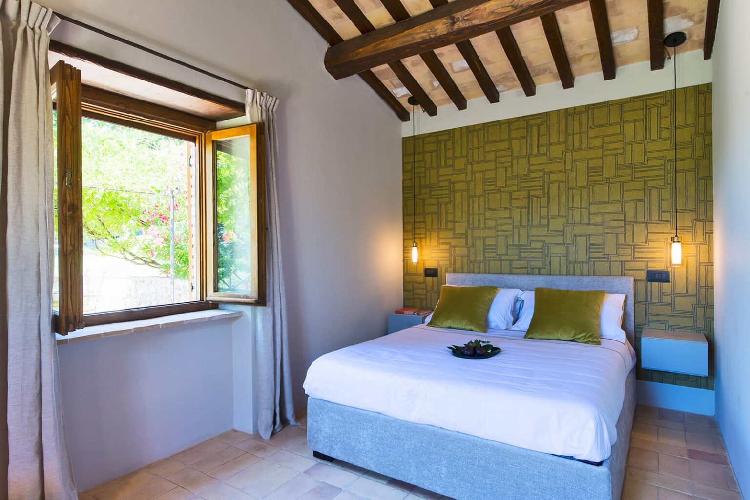Cozy bedroom with a large bed, green accent wall, wooden ceiling beams, and a window letting in natural light. Ideal for relaxation and comfort. | Only on SopranoVillas