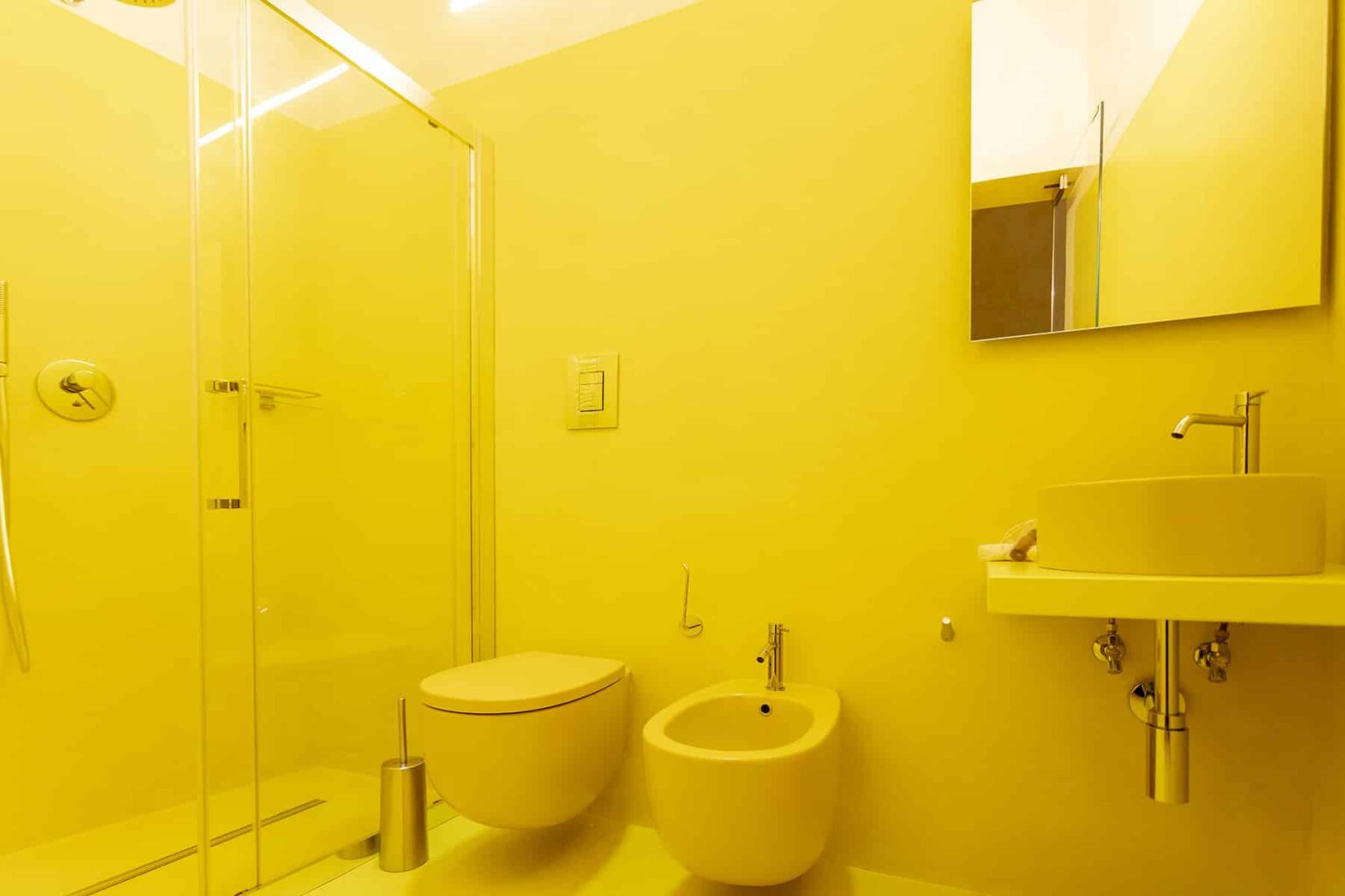 Bright yellow modern bathroom featuring a shower, toilet, and sink, with sleek fixtures and ample lighting. | Only on SopranoVillas