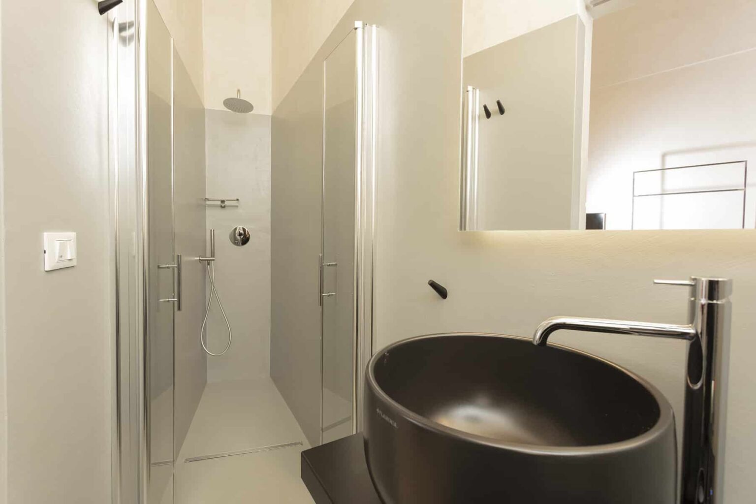 Modern bathroom interior featuring a sleek black freestanding sink, glass shower enclosure, and minimalist design elements. | Only on SopranoVillas
