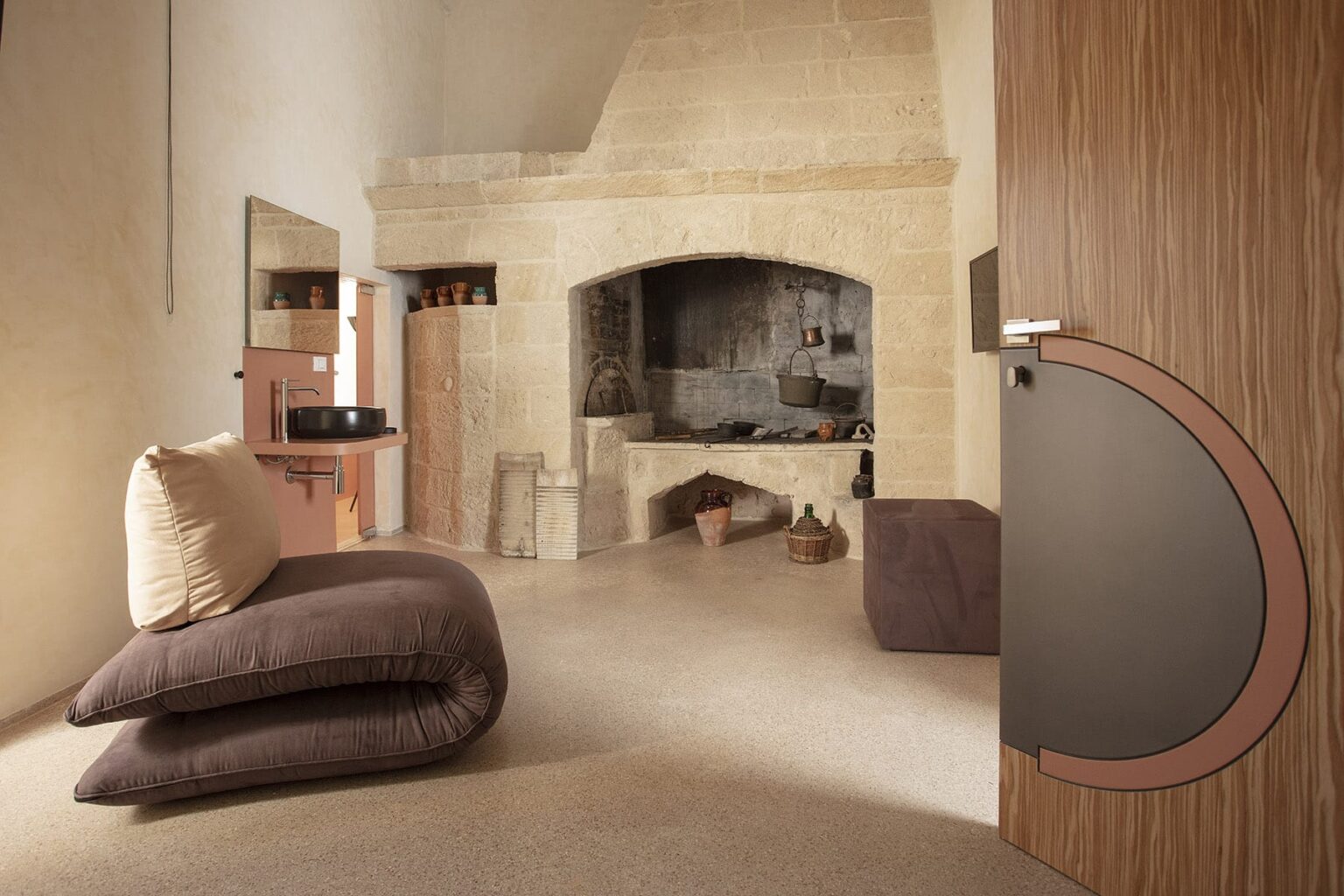 Cozy interior design featuring a modern living space with a stone fireplace, soft cushions, and a stylish wooden door, creating a warm and inviting atmosphere. | Only on SopranoVillas