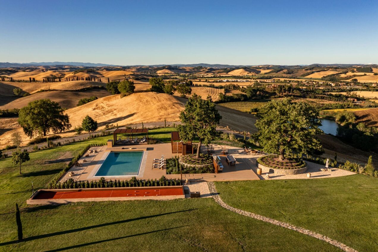 Aerial view of a luxurious backyard featuring a swimming pool, landscaped gardens, and scenic hills in the background, ideal for outdoor relaxation and entertainment.