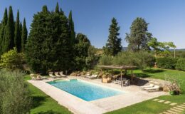 Luxurious outdoor pool surrounded by lush greenery, sun loungers, and a shaded seating area, ideal for relaxation and leisure in a serene garden setting.