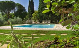 Serene backyard oasis featuring a crystal-clear swimming pool surrounded by lush greenery, stone pathways, and comfortable lounge chairs, ideal for relaxation and outdoor gatherings.