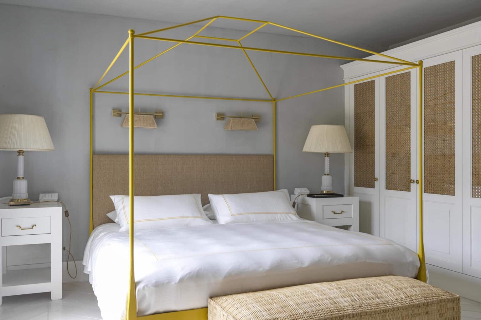 Modern bedroom featuring a yellow canopy bed, white linens, and stylish nightstands. The room has neutral walls, a large wardrobe, and elegant lamps, creating a serene and inviting atmosphere. | Only on SopranoVillas