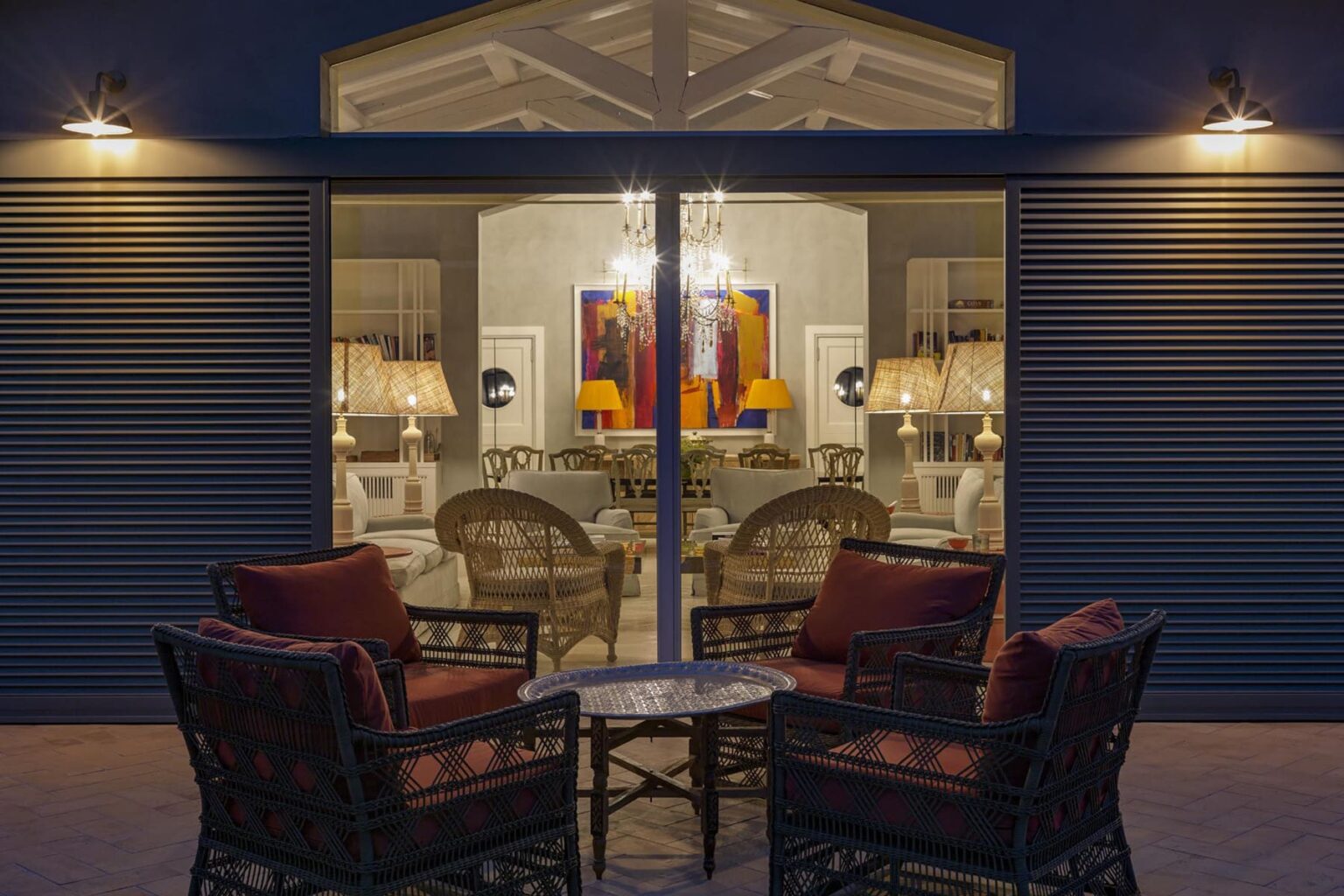 Cozy outdoor seating area with two wicker chairs and a glass table, showcasing a stylish interior with modern decor and warm lighting. | Only on SopranoVillas