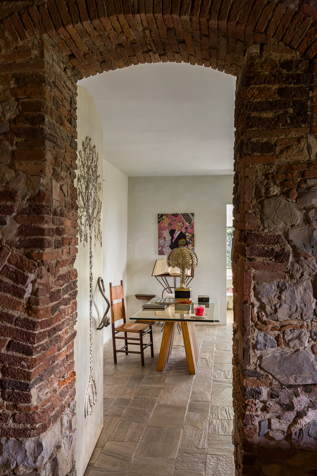 Cozy interior view showcasing a rustic room with exposed brick walls, a wooden chair, a glass table, and an art piece on the wall, creating an inviting workspace atmosphere. | Only on SopranoVillas