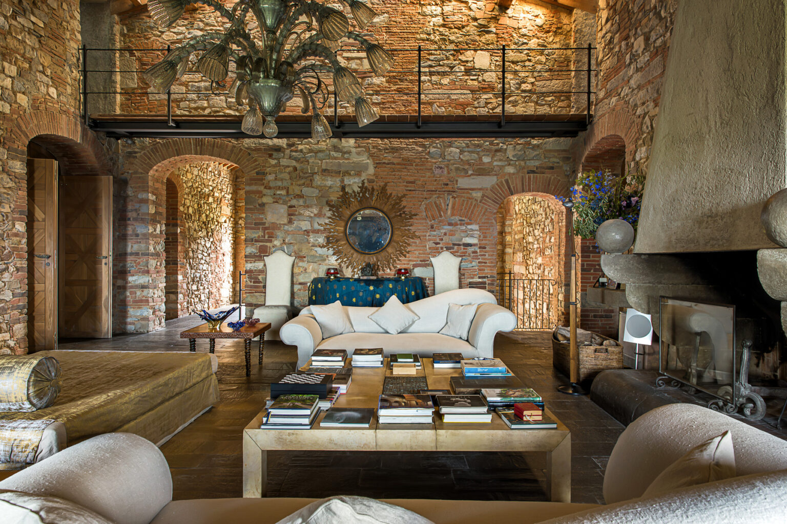 Spacious living room featuring rustic brick walls, a cozy white sofa, an elegant coffee table with books, and unique decorative elements, creating a warm and inviting atmosphere. | Only on SopranoVillas
