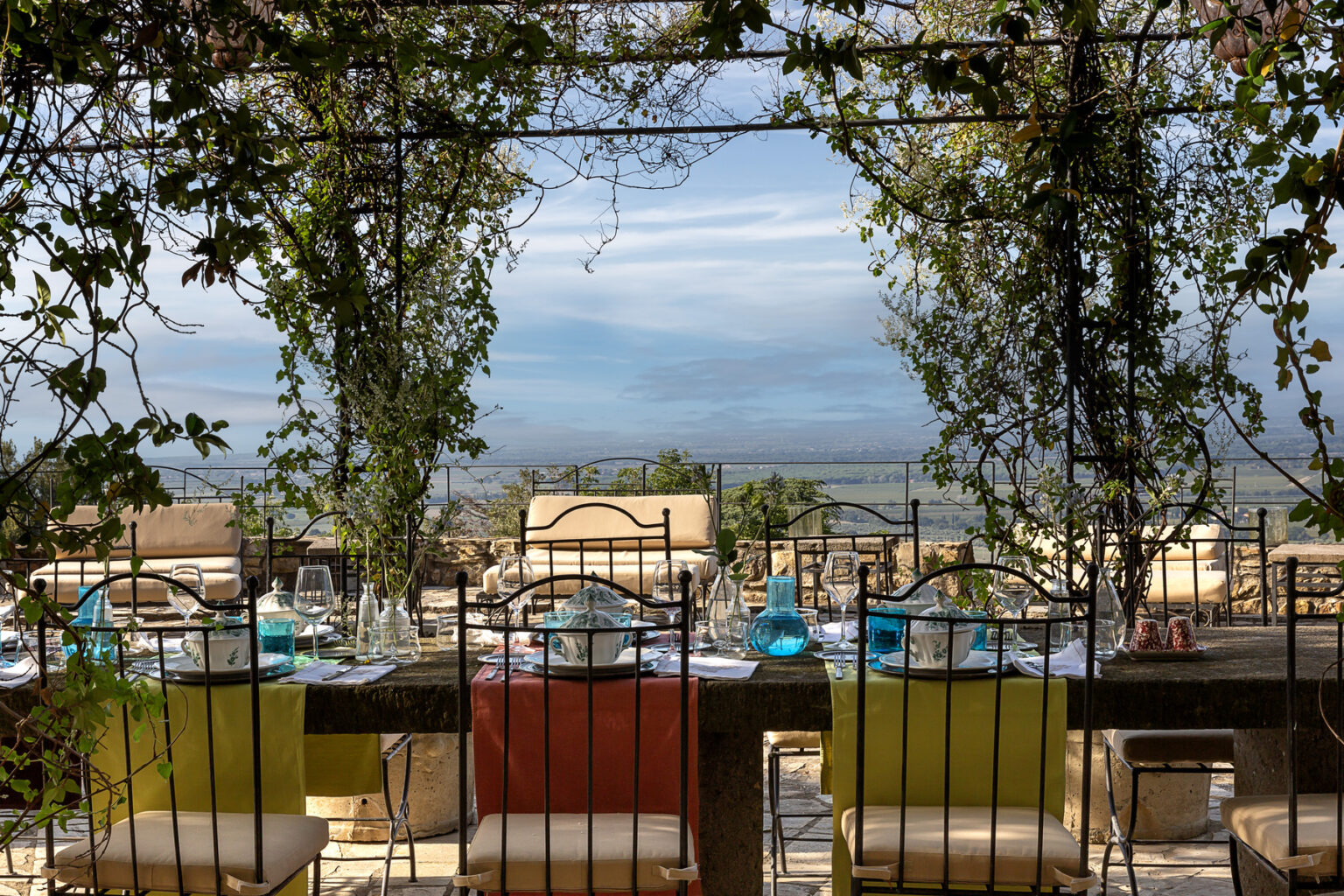 Outdoor dining area with a scenic view, featuring colorful table settings and lush greenery, ideal for a relaxing meal in nature. | Only on SopranoVillas