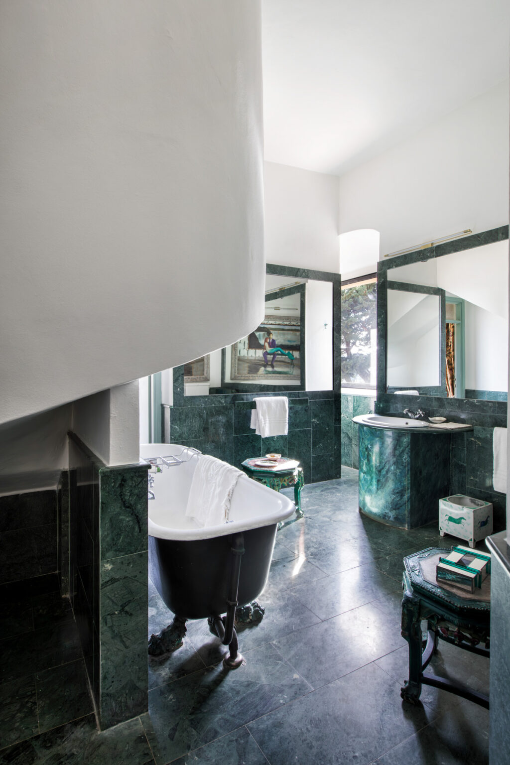 Modern bathroom with a spiral staircase, featuring a freestanding bathtub, green marble walls, and stylish mirrors. | Only on SopranoVillas