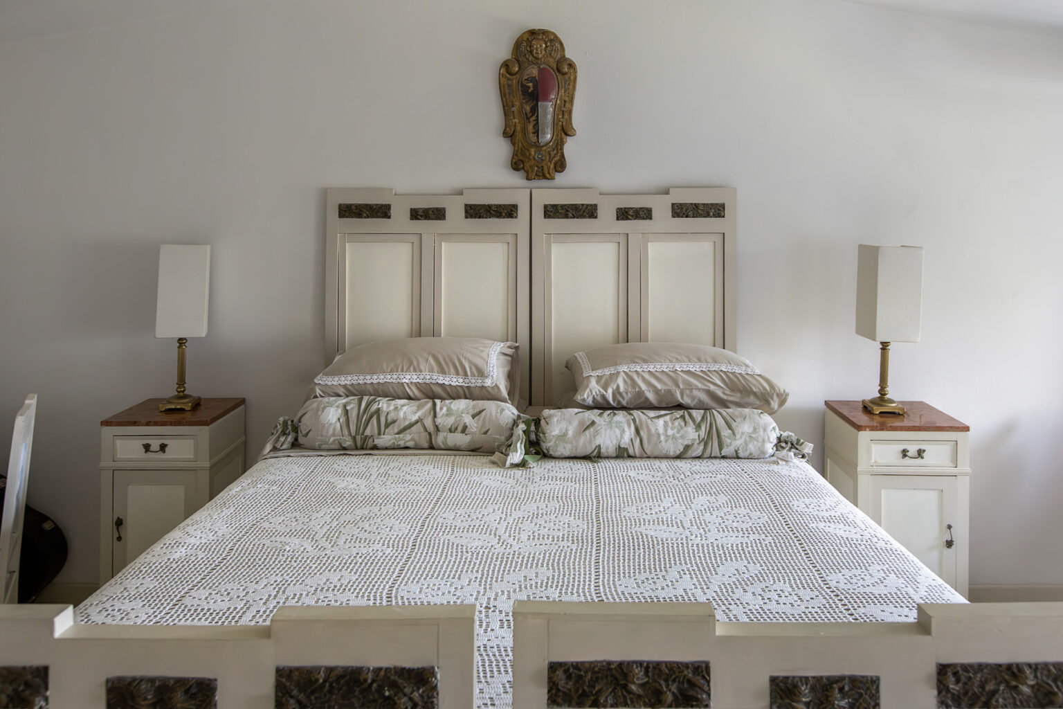 Elegant bedroom featuring a large, double bed with decorative headboards, adorned with plush pillows and a light-colored quilt. Two matching bedside tables with lamps are positioned on either side, enhancing the serene atmosphere of the room. | Only on SopranoVillas