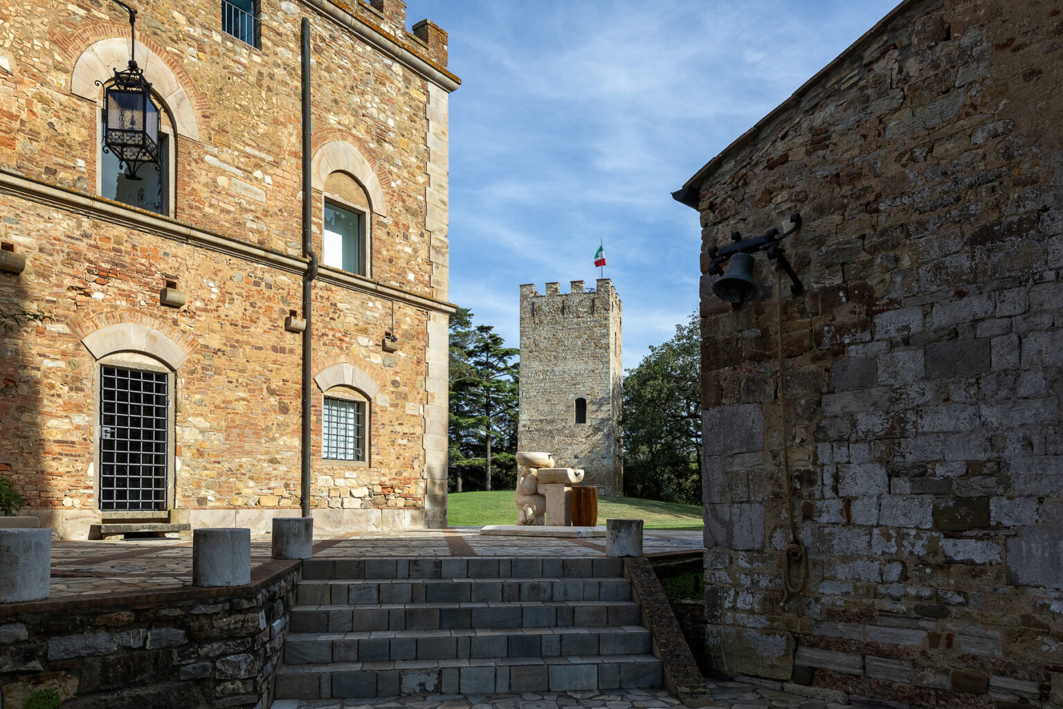 Historic stone buildings and a medieval tower surrounded by greenery, with a clear blue sky in the background. The image captures the architectural details and the serene atmosphere of the location, ideal for heritage tourism. | Only on SopranoVillas