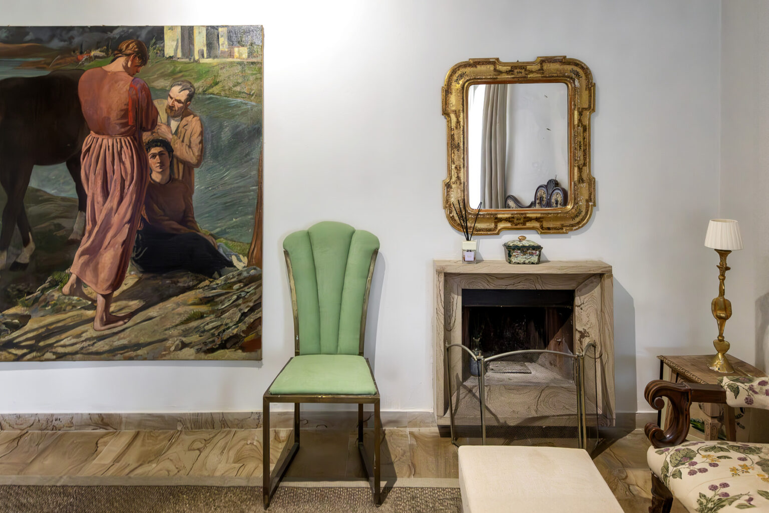 Interior view featuring a green vintage chair, a large painting depicting a rural scene, a decorative gold-framed mirror, and a cozy fireplace, creating an elegant and inviting atmosphere. | Only on SopranoVillas