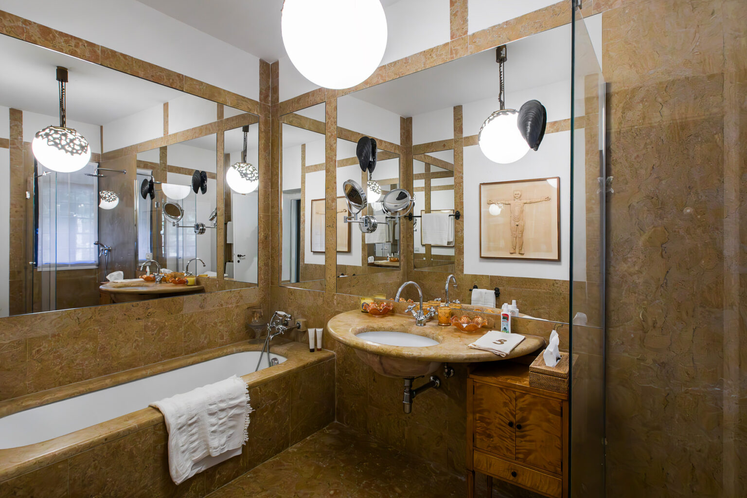 Modern bathroom featuring a spacious design with a freestanding bathtub, a stylish wooden vanity, and elegant lighting fixtures. The warm tones of the walls and accents create a cozy atmosphere, complemented by decorative elements like fresh fruits on the countertop. | Only on SopranoVillas